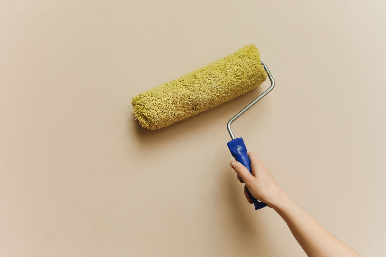 Paint roller against a warm beige wall